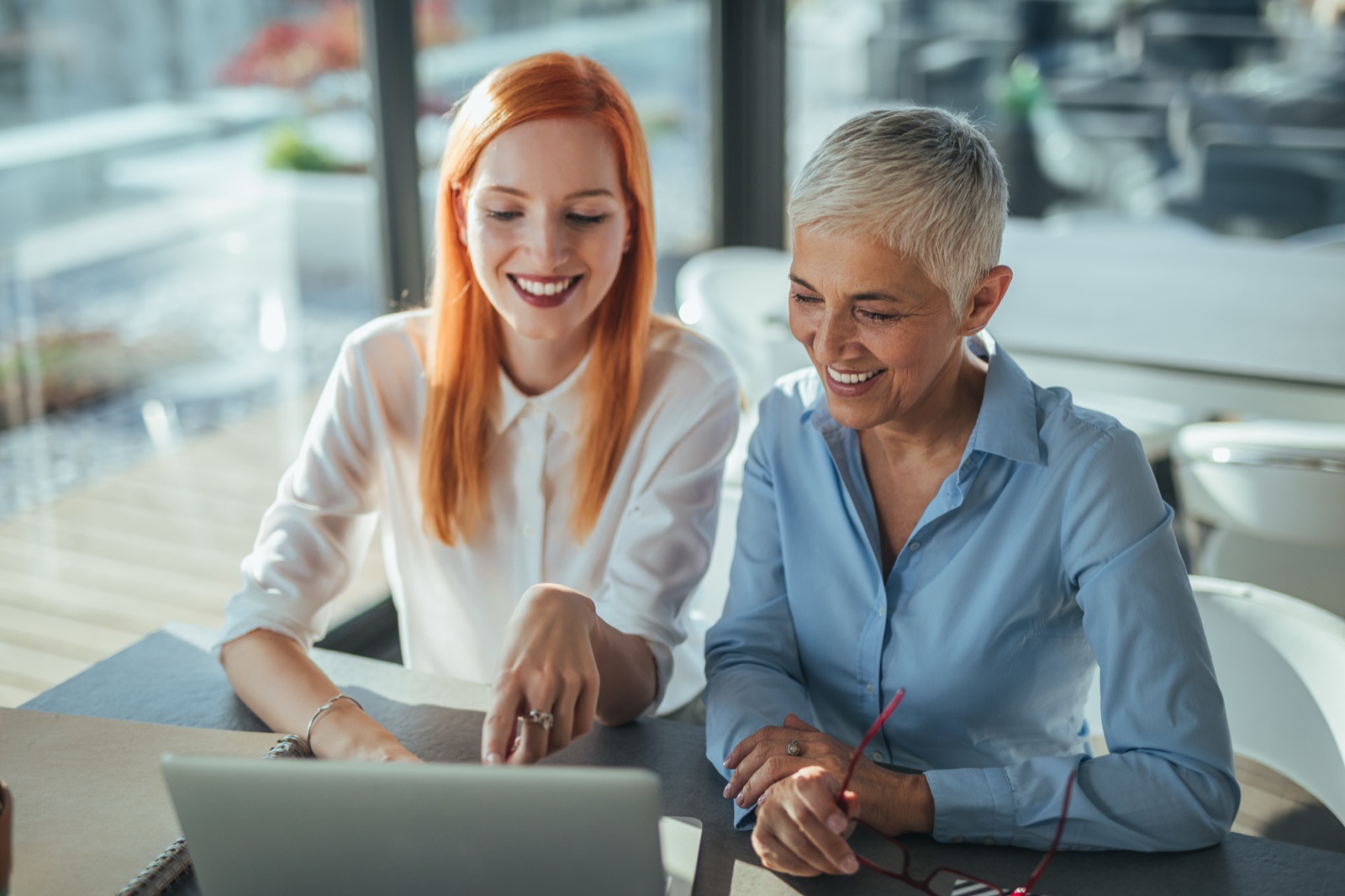 Two colleagues collaborating at a laptop in a bright modern office