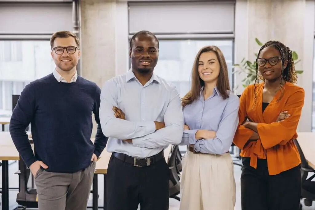 Four colleagues standing together in a modern office, representing a UK workplace preparing for the strengthened duty to prevent sexual harassment
